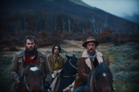 still from The Settlers film; 3 men on horseback in a mountainous terrain